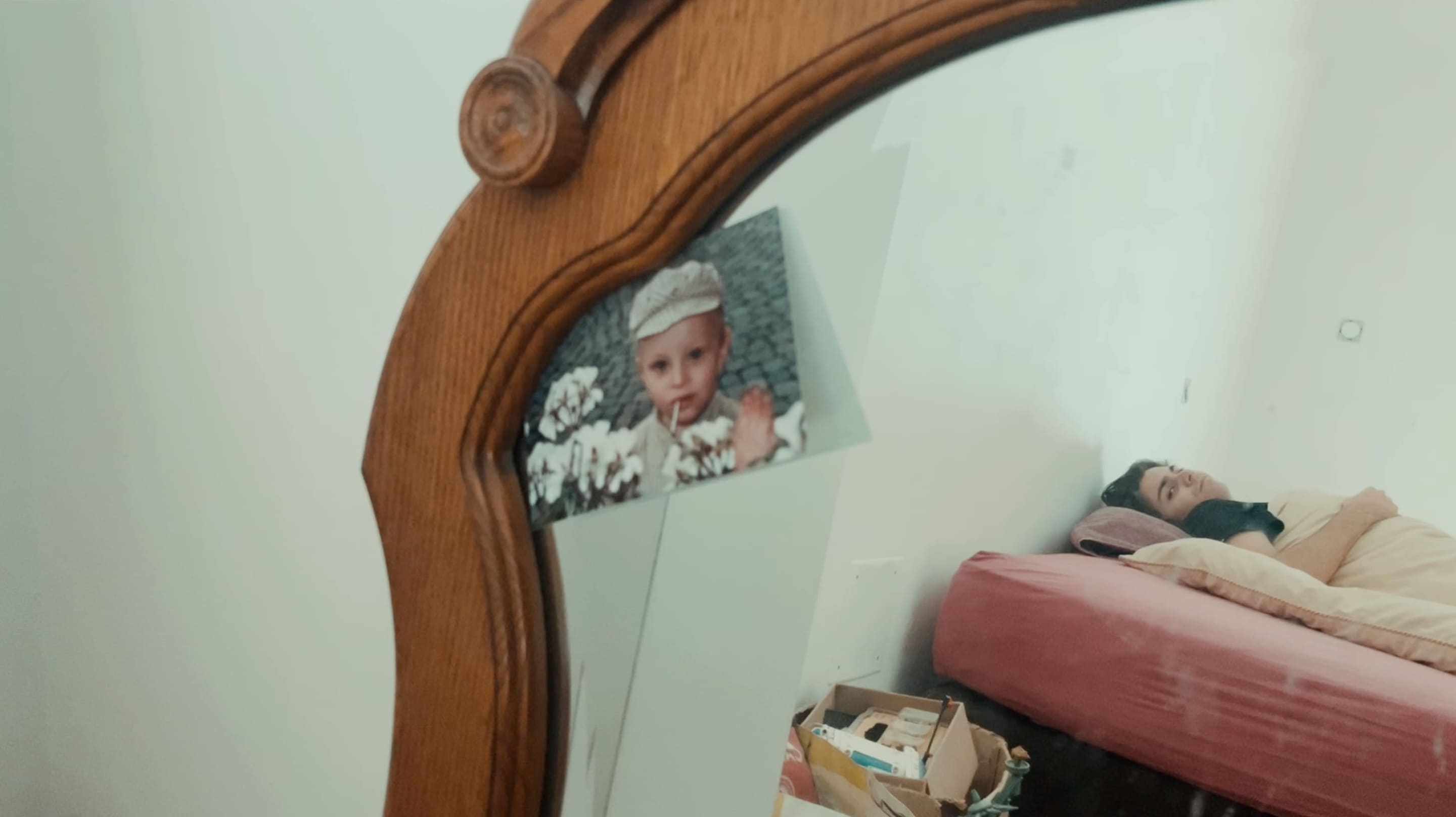 2e photographie d'Anemoia où on voit le reflet d'un homme qui regarde une photo d'un enfant qui se trouve sur un miroir.