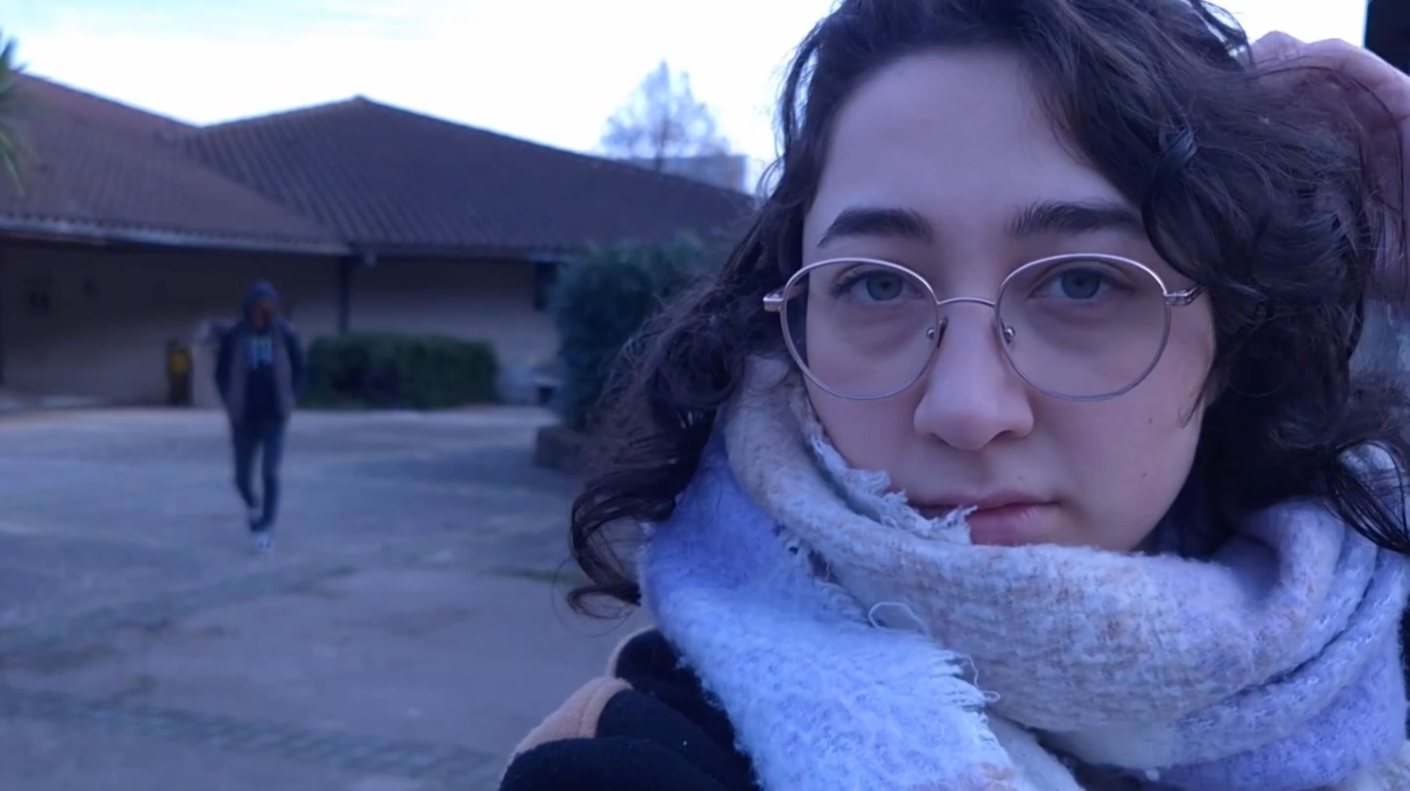 Image tirée de Presence où femme en gros plan regarde l’objectif de la caméra. Derrière elle l’on peut apercevoir quelqu’un de mystérieux.